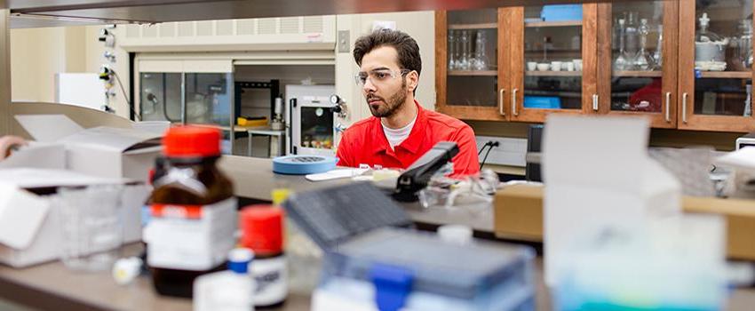 Male student with safety glasses on in a lab.