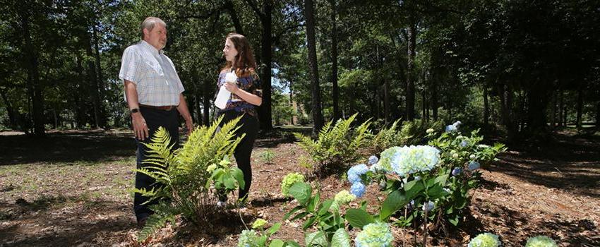 Dr. Kevin White, right, professor and chair of the department of civil, coastal and environmental engineering, and Jordan Blackmon, sophomore civil engineering major, stand on the edge of one of five landscaped bioinfiltration swales near Meisler Hall. The swales help capture storm water runoff instead of it running off on the surface and eroding soil that eventually deposits into Three Mile Creek.