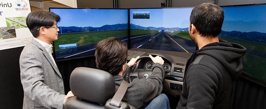 Civil Engineering students using the driving simulator with professor.