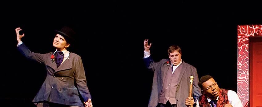 USA Students acting on stage in a play with players holding up hands while one is kneeling on the floor.