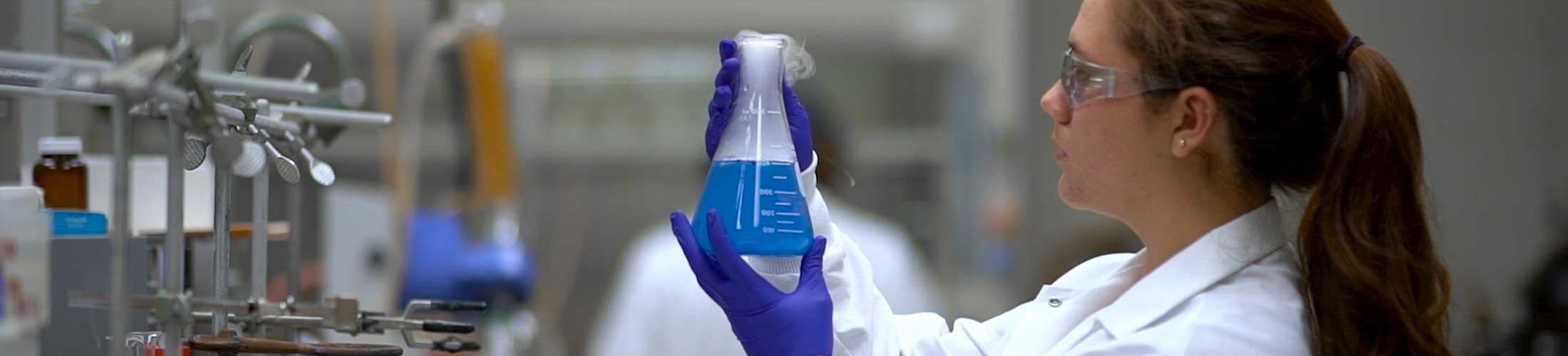 Female student holding a beaker in lab.