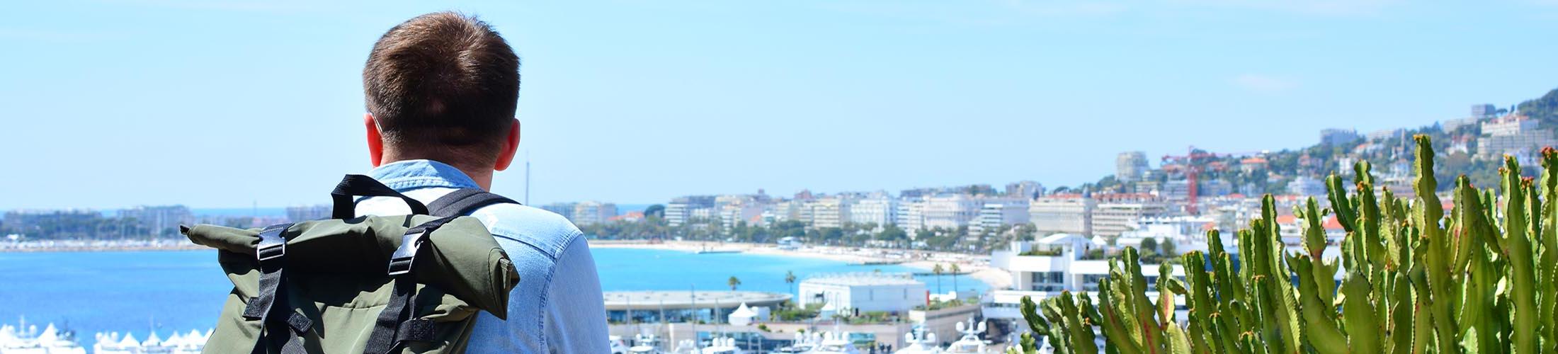 Male wearing backpack and looking out over shoreline.