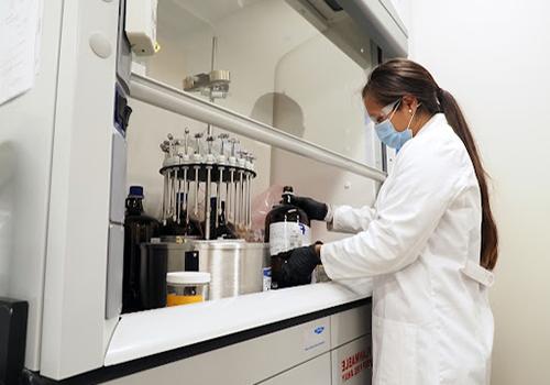 Student working in lab with white coat on.