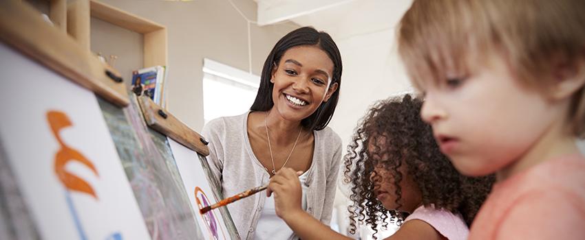 Teacher working with students painting.