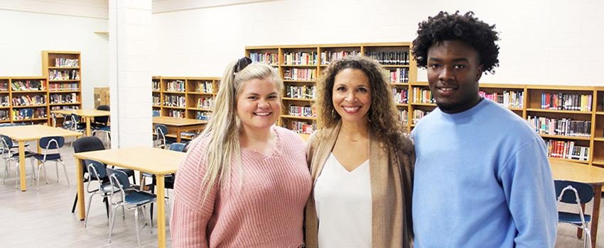 Two students with a school counselor in the library,