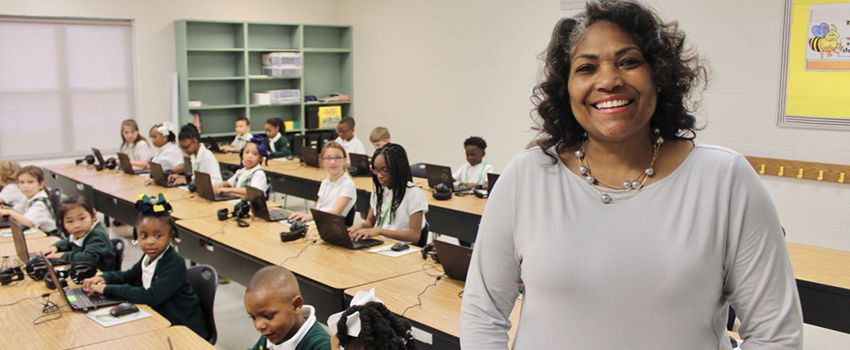 Teacher standing in front of her class of children at desks.