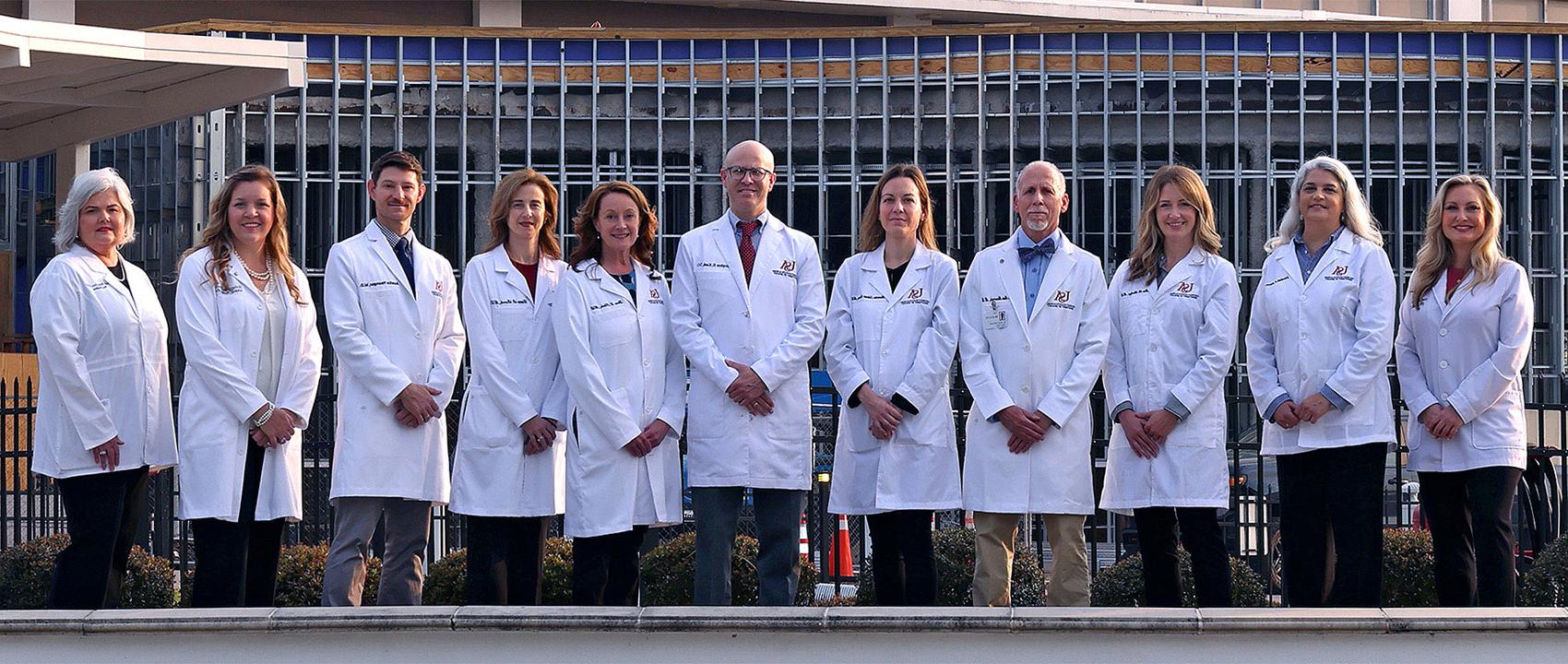 The faculty of the USA Department of Urology stand in front of USA Health University Hospital.