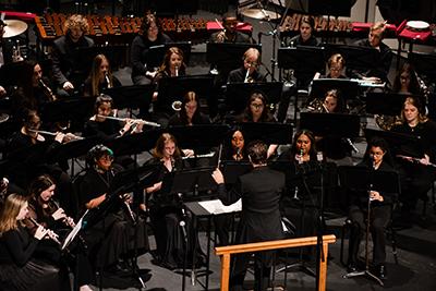 Students playing instruments with conductor.