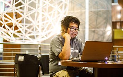 Student Working in lobby on laptop.