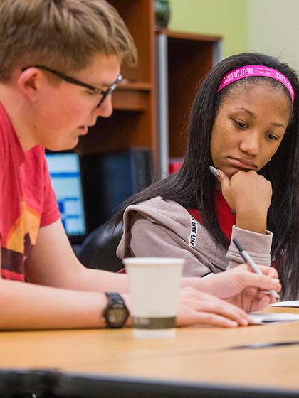 Advisor helping student while they are looking at paper.