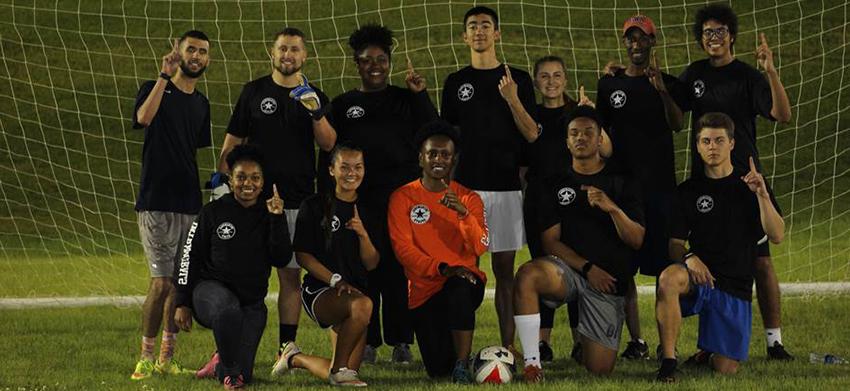 Students in front of the soccer goal holding up number 1 with hands