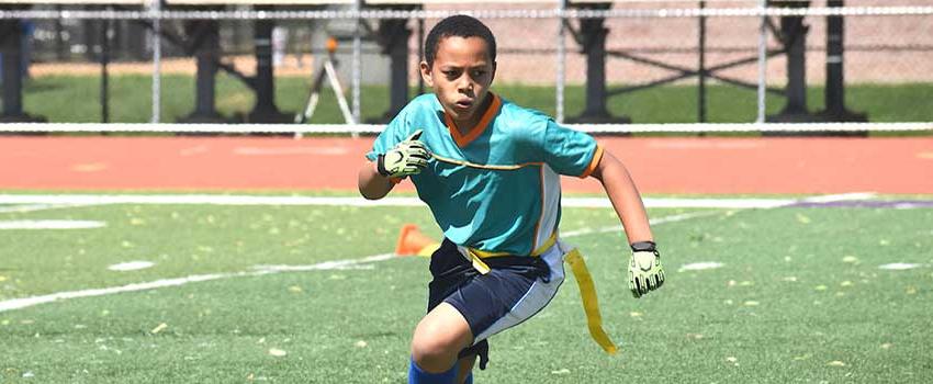 Young boy running playing flag football.