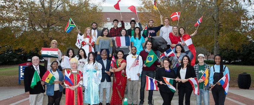 International Students in front of the Mitchell Center with flags