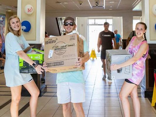 Students carrying boxes in hall