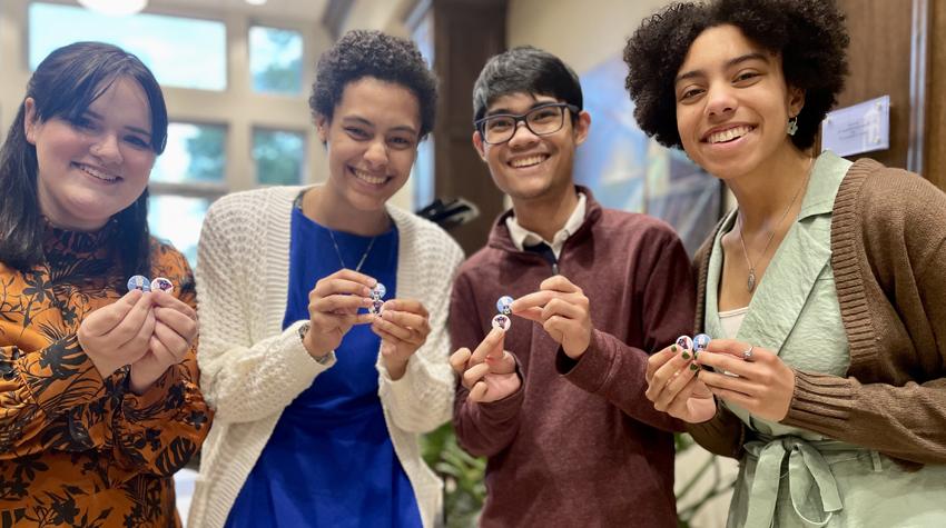 Four students holding buttons given to them by President Bonner.