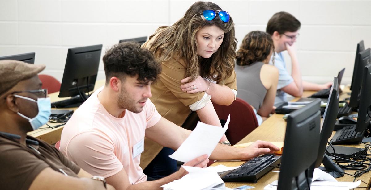 Margaret Bradford, site coordinator for the VITA program at the University of South Alabama, helps Kobe Cox, an accounting major and student volunteer, fill out a tax return for a Mobile resident.