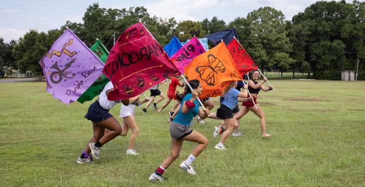 Members of each of the 12 groups of students carry the colorful flags they made at the Honors College retreat. The flags will eventually hang in the Bethel, the Honors College headquarters.