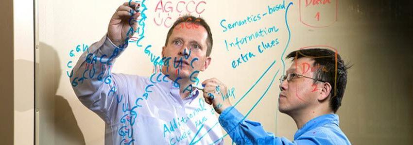 Dr. Huang and Dr. Borchert writing on a board