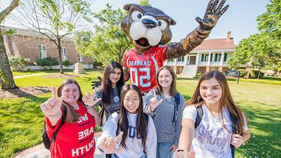 Five students holding up J sign for Jaguars in front of the Southpaw statue.