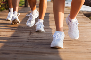 White tennis shoes running on a boardwalk.